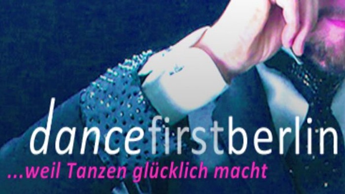 Ein Mann mit Bart und weißem Hemd tanzt, während er ein Handy hält.