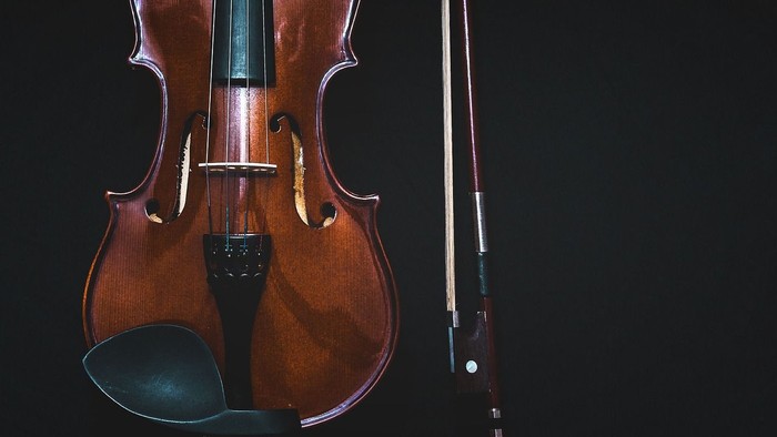 A violin and bow against a dark background.