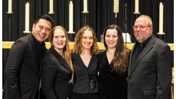 Eine Gruppe von fünf Personen posiert vor einem Kirchenaltar.