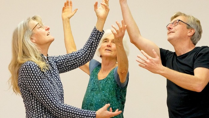 Drei Menschen tanzen fröhlich in einem Raum