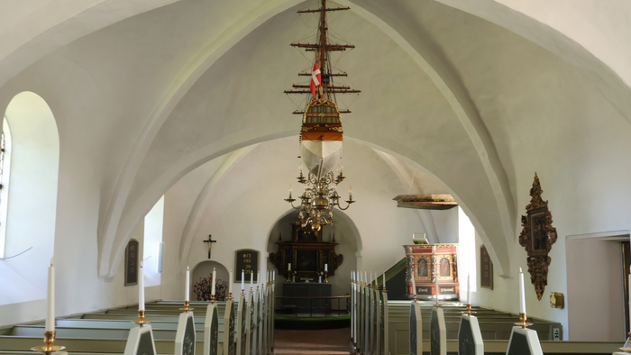 Indenrig af kirke med hvidt tag, alter og kælderkirke.