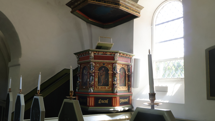 En prædikestol i en kirke med udsmykning og lys fra vindue