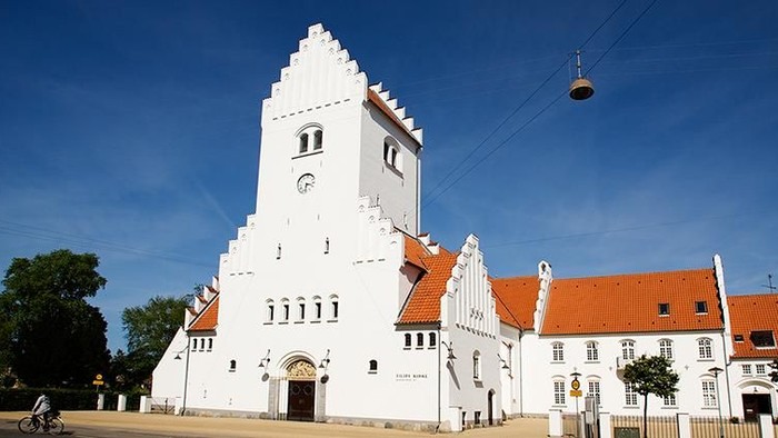 Et hvidt kloster med spisse tårne og røde tag, beliggende under en klar blå himmel