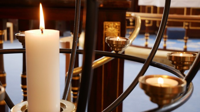 En lysende stålleker med flere lille lyster i en kirke.