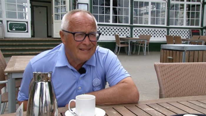 En mand sidder udenfor og ser glade ud.