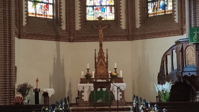 Innenraum einer Kirche mit Altarraum und Buntglasfenstern