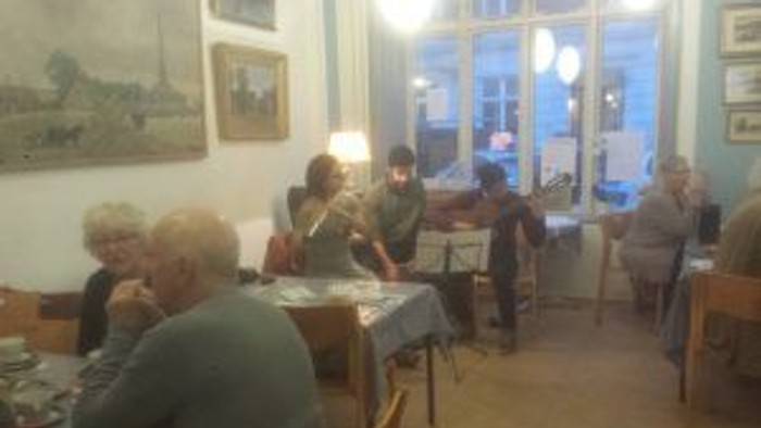 En gruppe ældre folk sidder og spiser i et restaurant.