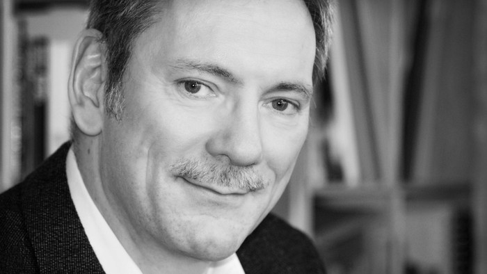 En svart og hvid portrætfoto af en mand i formel klædning.