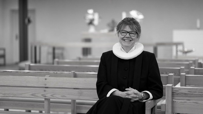 En kvinde i mørkt tøj sidder i en kirke.