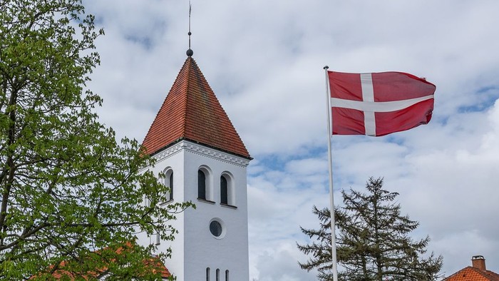 Tårn med klokke og dansk flag på en klar dag