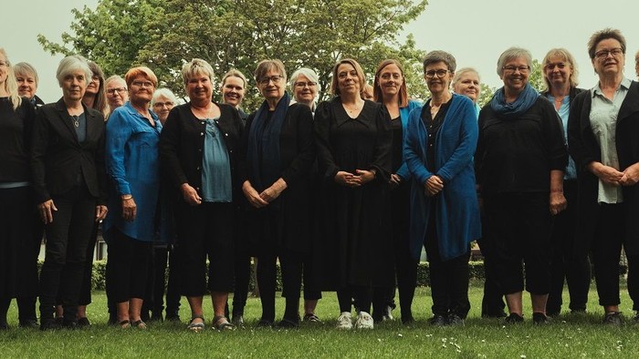 En gruppe af mænd og kvinder står sammen i en park.