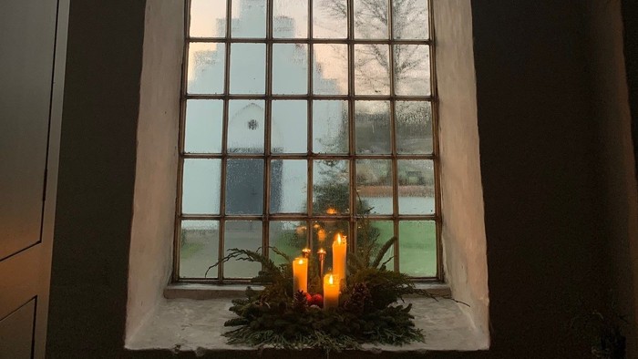 Et vindueskarm med en lille juletree og lys.