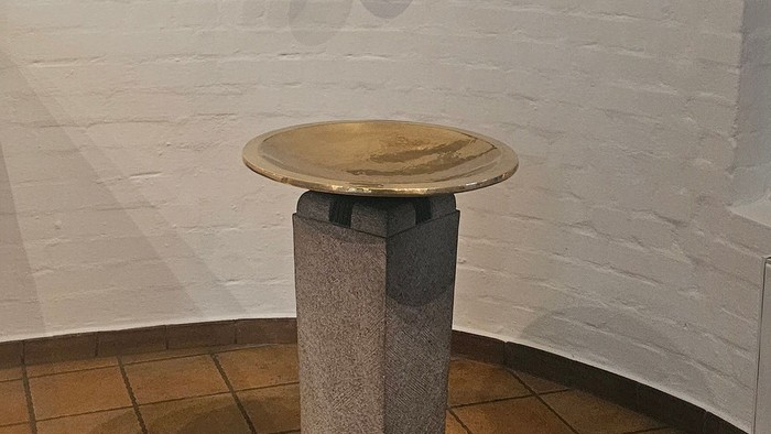 Ein goldener Pokal steht auf einem Sockel unter einem weißen Ziegelwand