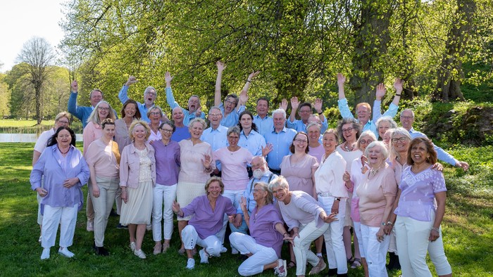 En stor gruppe af kvinder i rosa og hvidt samlet i en park
