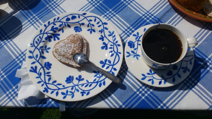 En kaffekop og en småkage på en blå og hvid servise.