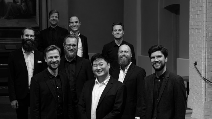 En gruppe mænd i formelt tøj poserer sammen i sort-hvid foto