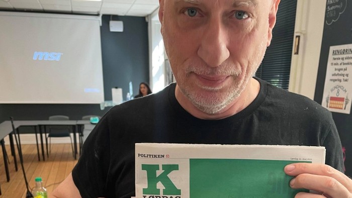 Mand holder et grønt papir med en budskab i spansk