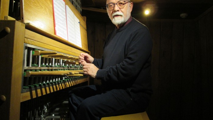 Mann spielt Orgel in dunklem Raum