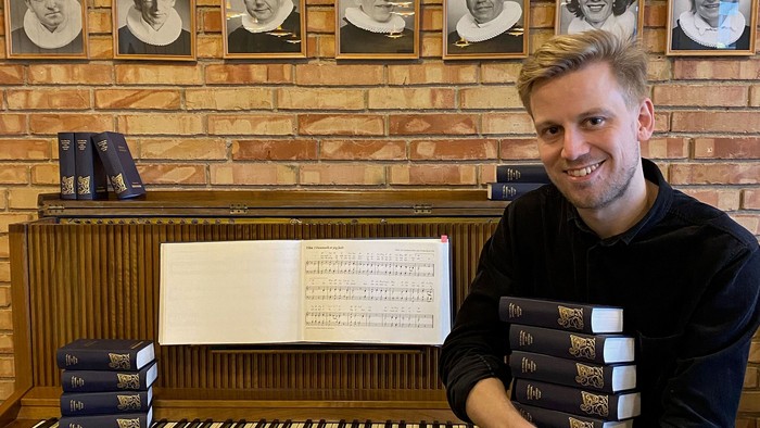 Mand sitter ved piano med kaffe.