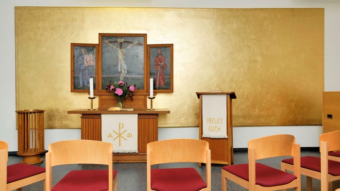 Kirchliche Innenansicht mit Altar, Bildern und Stühlen