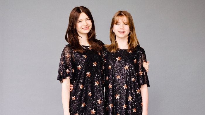 Zwei Mädchen in schwarzen Kleidern mit Sternenmuster stehen nebeneinander.