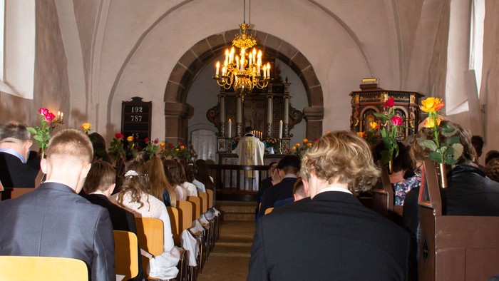 En kirke med folk, der sidder på gulde stolene og ser mod alteret.