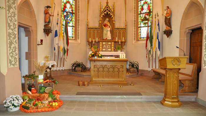 Innenraum einer Kirche mit Altar, Statuen und farbenfrohen Fenstern