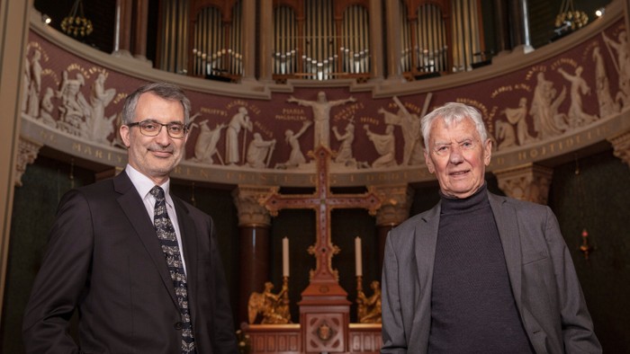 To men står foran en stor orgel med udsmykning.