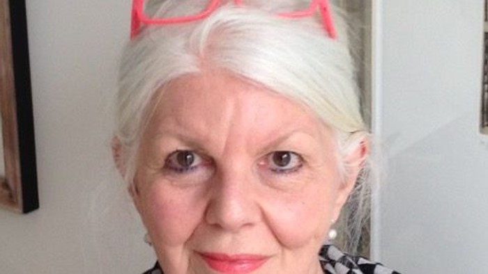 En kvinde med blåbrønde og røde briller laver selfie.