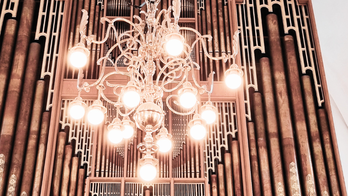 En stor og luksuriøs kælderkandelier hænger fra loftet i et rum med høje vinduer.