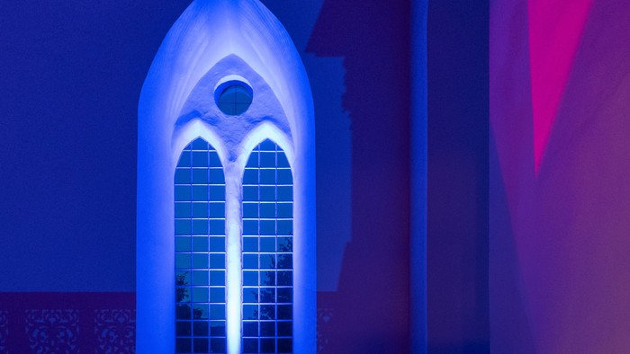 Ein beleuchtetes gotisches Fenster in einem Gebäude bei Nacht