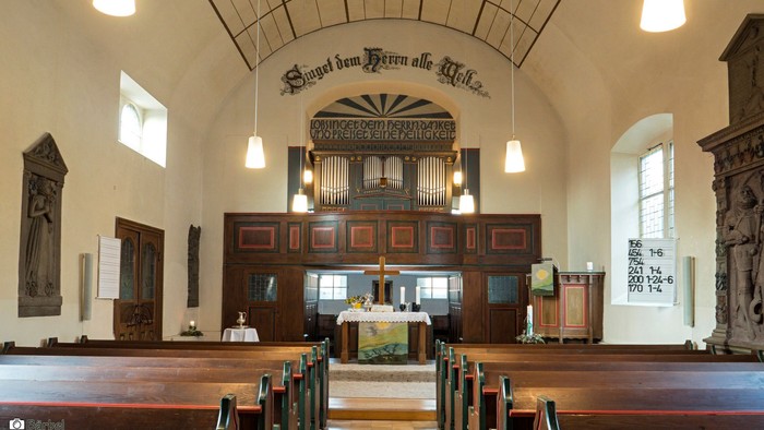 Kircheninneres mit hölzernen Kirchenbänken, Altar und Orgel