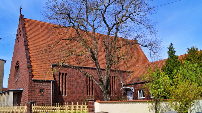 Ein rotes Backsteingebäude mit spitzen Dächern und einem Baum davor
