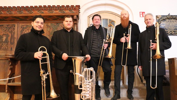 Fünf Musiker posieren mit ihren Instrumenten in einer Kirche