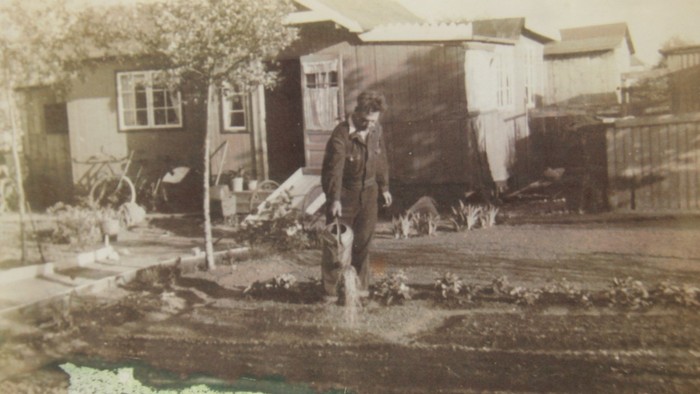 En mand går i en muddervej med hunde i en lille by.