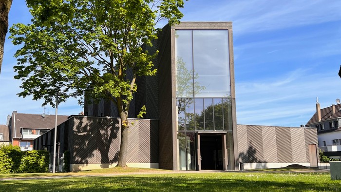 Modernes Gebäude mit großem Glasfenster und grünem Rasen im Vordergrund