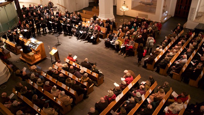 Große Versammlung in einem Saal mit vielen Menschen, die in Reihen sitzen