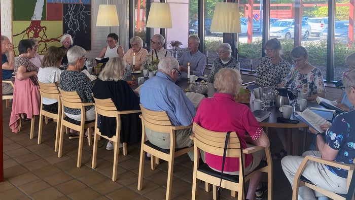 En gruppe mennesker sidder i et café og spiser.