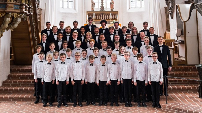 En kor med mænd og kvinder i formel klædning poser i en kirke