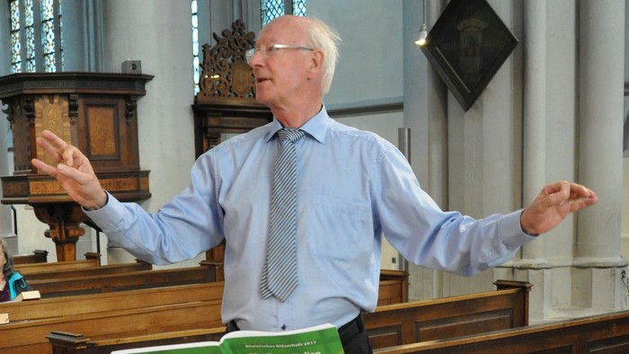 Mann dirigiert Chor in Kirche