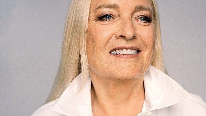 En kvinde med blond hår og et hvidt blus.