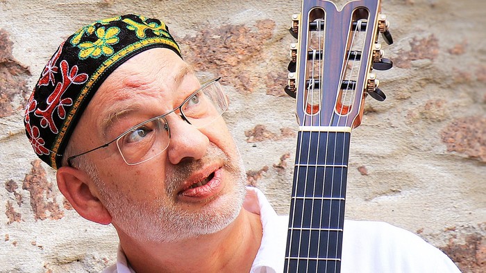 Mann mit Brille und Hut spielt Gitarre