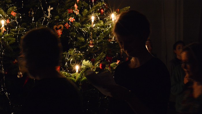 Børn ser julenisse ved juletree