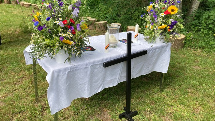 Blumengeschmückter Altar mit Kerzen und Holzkreuz.