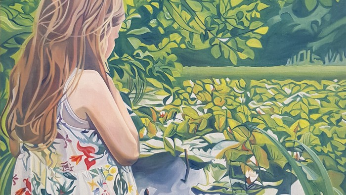 En kvinde med lang blond hår står i en trækrans og ser ud over et grønt landskab.