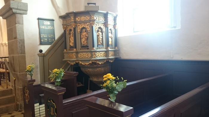 En prædikestol med udsmykning og blomster i kirke.