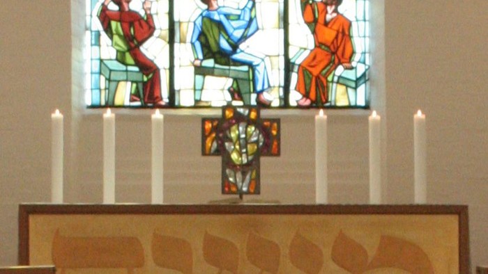Farverige vinduesglasskærm i kirke med lysende farver og billeder af mennesker