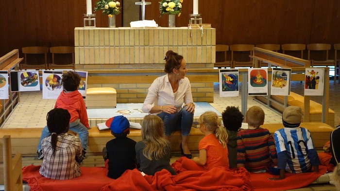 En kvinde læser for en gruppe børn i en kirke.