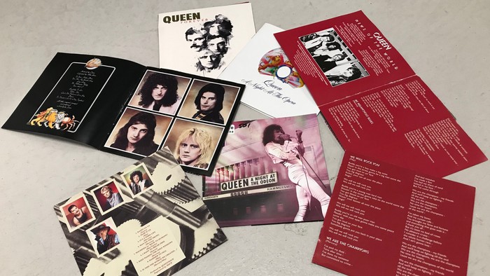 Billedet viser forskellige albumhuller og opslag fra Queen-album.