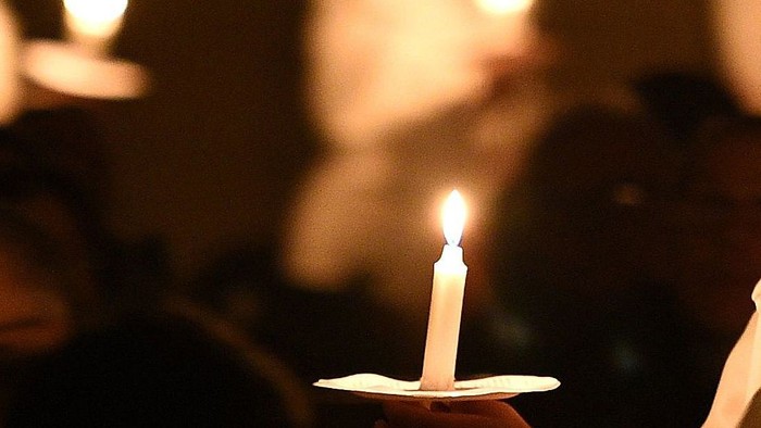 En person holder en lyse lyse i en stearinskål.